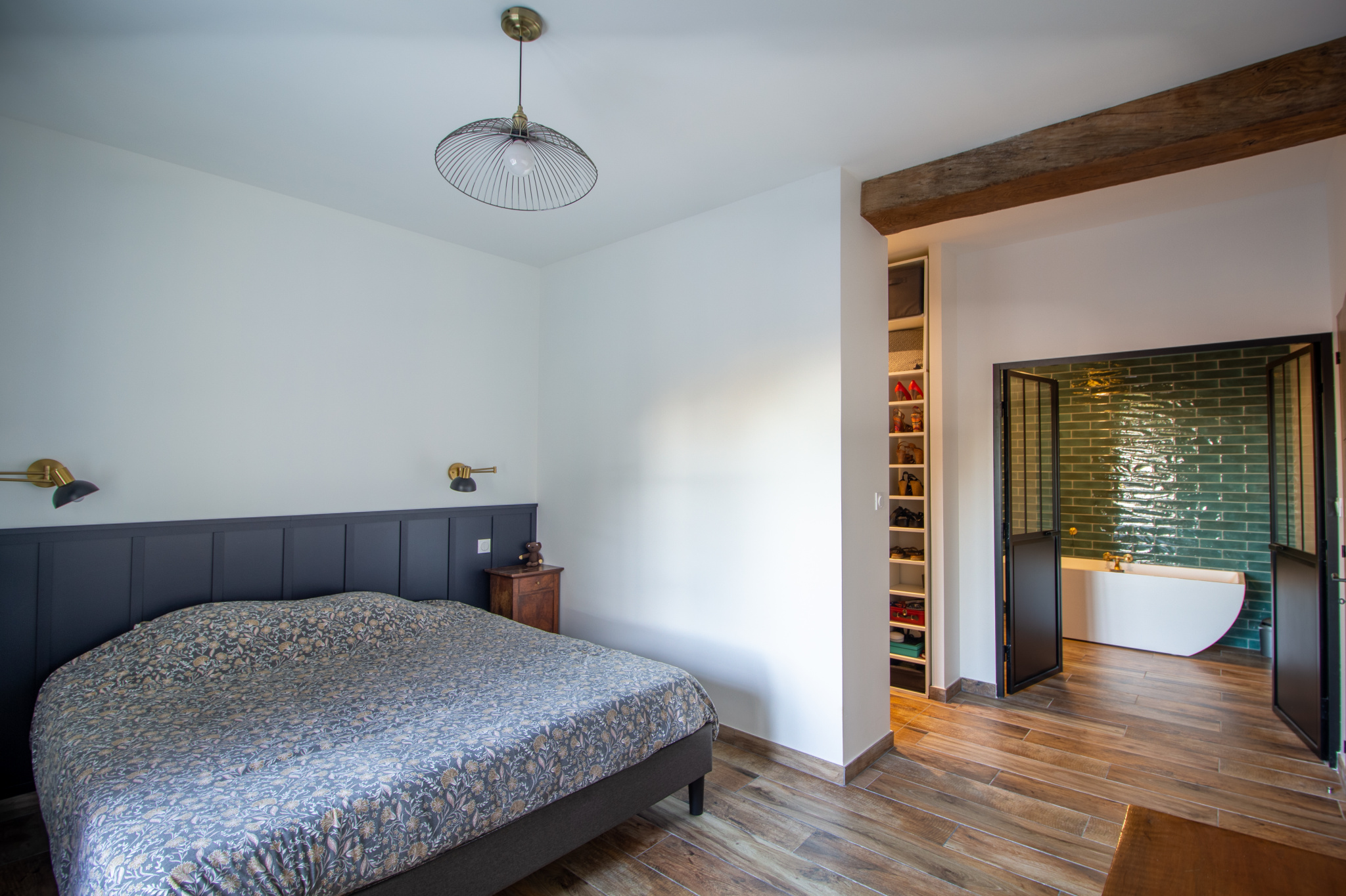Chambre d'une maison rénovée avec lit, éclairage et salle de bain attenante.