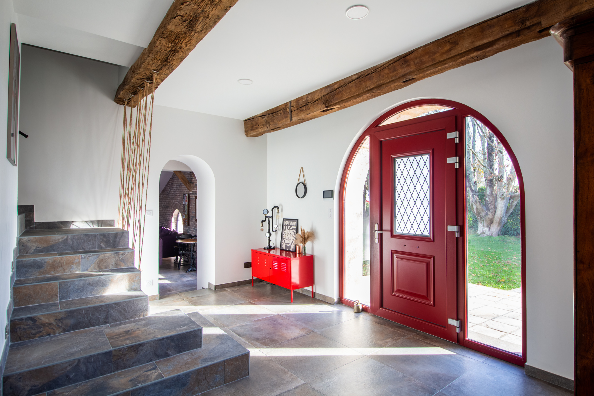 Intérieur d'une maison rénovée avec un hall d'entrée lumineux et des escaliers en pierre.