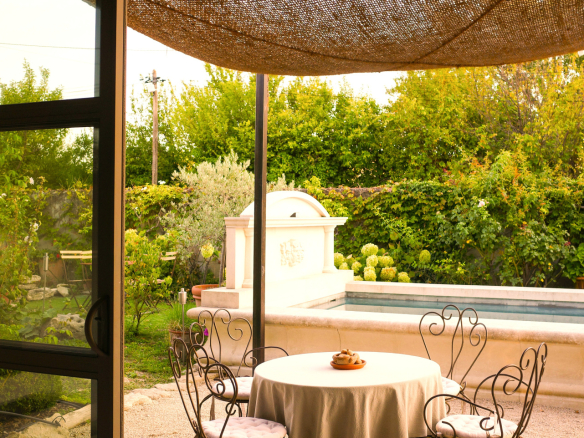 Terrace of a dry stone house with table and chairs, swimming pool in the background.