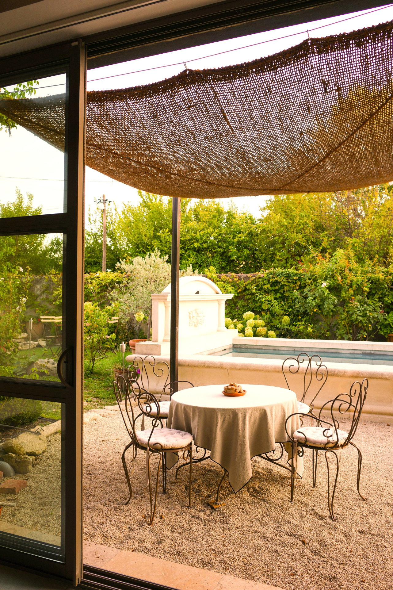 Terrace of a dry stone house with table and chairs, swimming pool in the background.