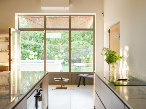 Interior of an Art Deco house with a modern kitchen and large bay windows overlooking a garden.