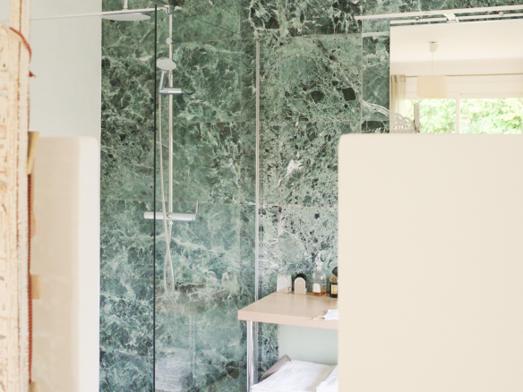 Modern bathroom with glass shower and green marble walls.