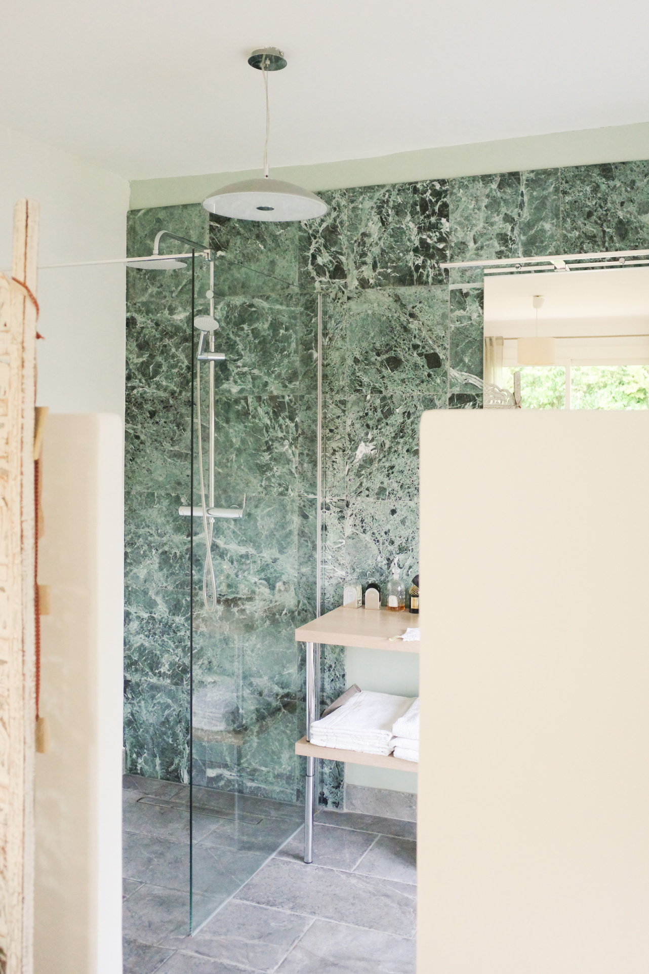 Modern bathroom with glass shower and green marble walls.