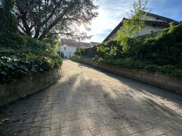Allée menant à une maison entourée de verdure à Roissy-en-Brie.