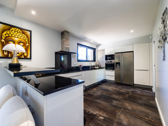 Intérieur d'une cuisine moderne et lumineuse avec un îlot central et des appareils électroménagers intégrés.