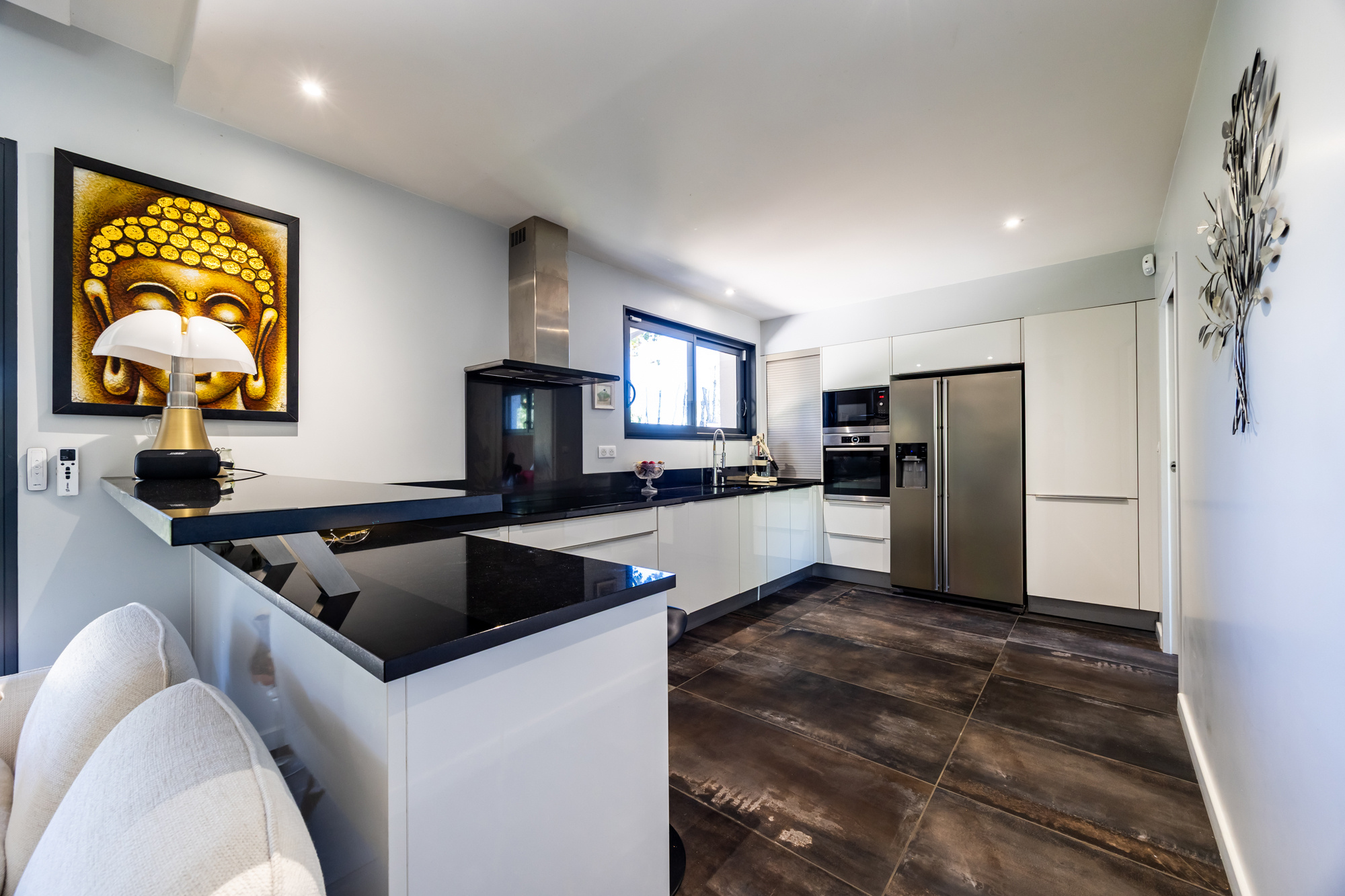Cuisine moderne dans une maison de plain pied Intérieur d'une cuisine moderne et lumineuse avec un îlot central et des appareils électroménagers intégrés.