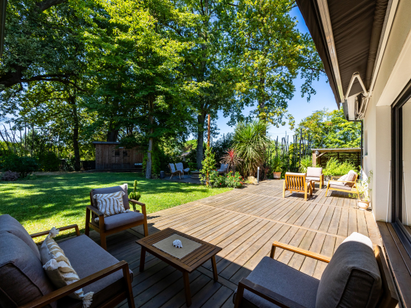 Terrasse en bois avec mobilier de jardin dans un jardin verdoyant.