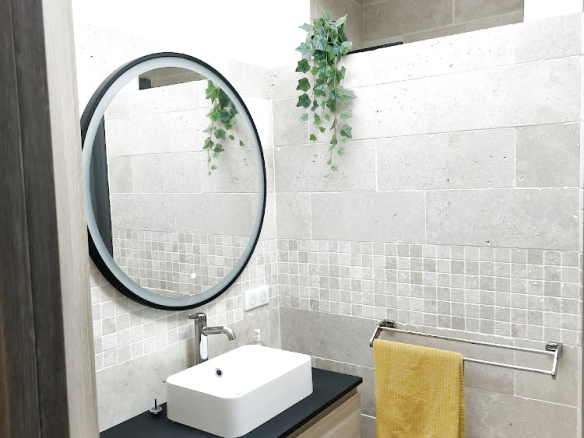 Salle de bain moderne avec meuble en bois, lavabo sur plan et miroir rond.