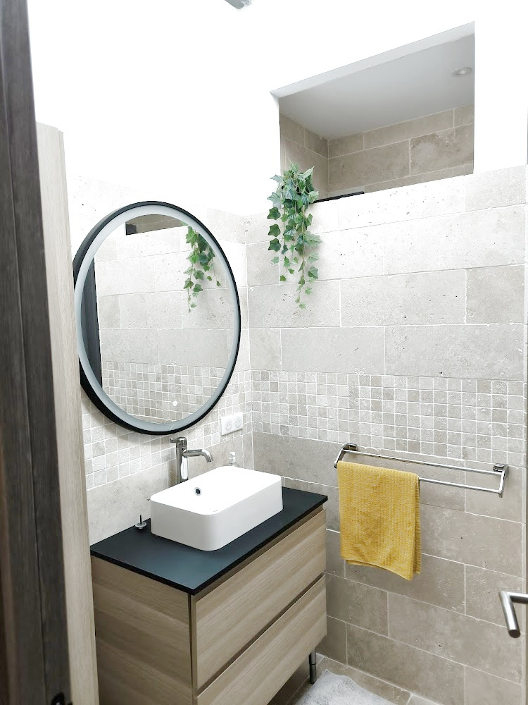 Salle de bain moderne Salle de bain moderne avec meuble en bois, lavabo sur plan et miroir rond.