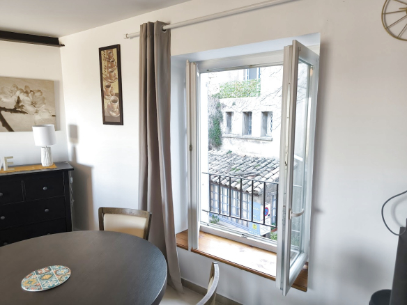 Vue intérieure d'un duplex à Bonnieux avec fenêtre ouverte sur un balcon et mobilier moderne.