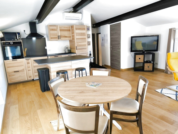Intérieur d'un duplex moderne avec cuisine ouverte, table à manger et salon, situé à Bonnieux.