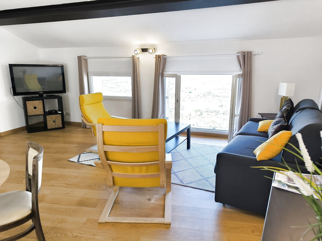 Salon d’un duplex à Bonnieux Intérieur d'un duplex à Bonnieux avec un salon moderne, canapé et fauteuil jaune, vue sur le village.