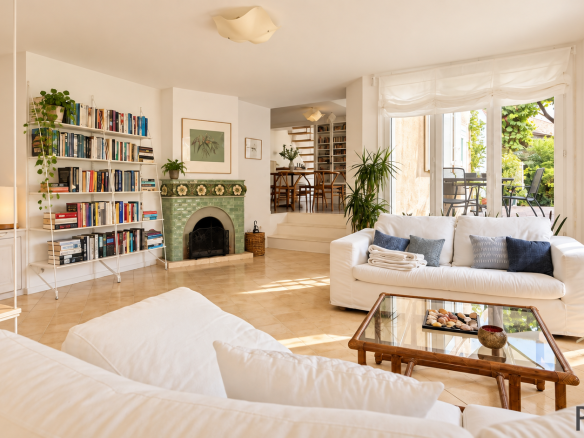Interior of a stone house with a bright living room, library and fireplace.