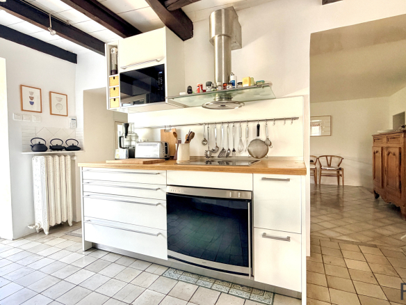Modern and bright kitchen in a stone house in Sergy, with white furniture and a wooden worktop.