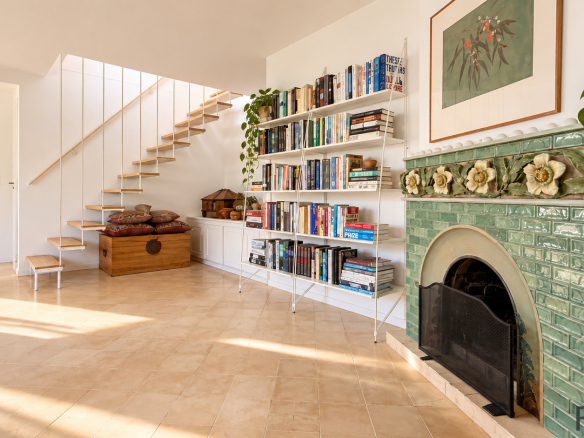 Interior of a stone house with staircase, library and decorative fireplace.