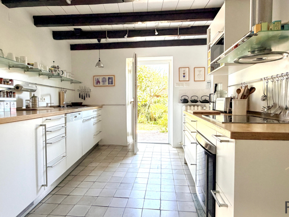 Modern kitchen with wooden worktops and garden view, stone house in Sergy.