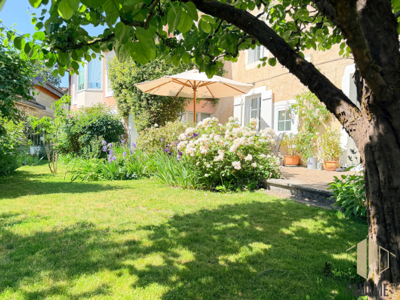 Garden of a stone house with parasol and flowers in Sergy.