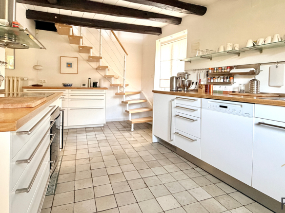 Modern kitchen in a stone house with a wooden staircase, located in Sergy.