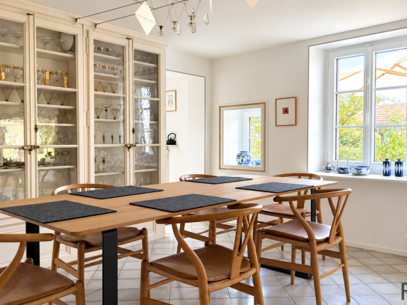 Interior of a stone house with a bright dining room and wooden chairs.