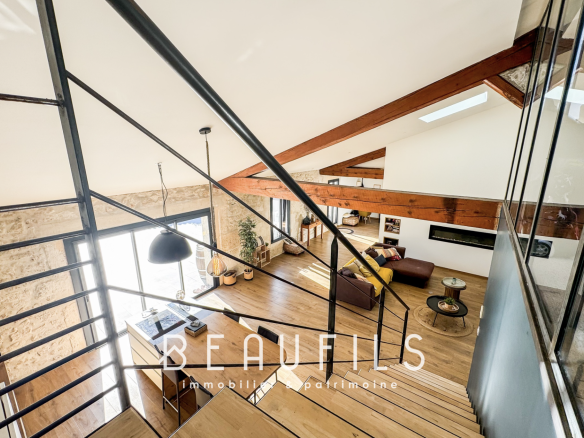 Vue intérieure d'un loft atypique avec escalier en métal et poutres apparentes.