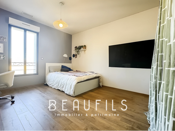 Chambre d'un loft atypique avec un lit et un bureau, murs clairs et fenêtre laissant entrer la lumière.