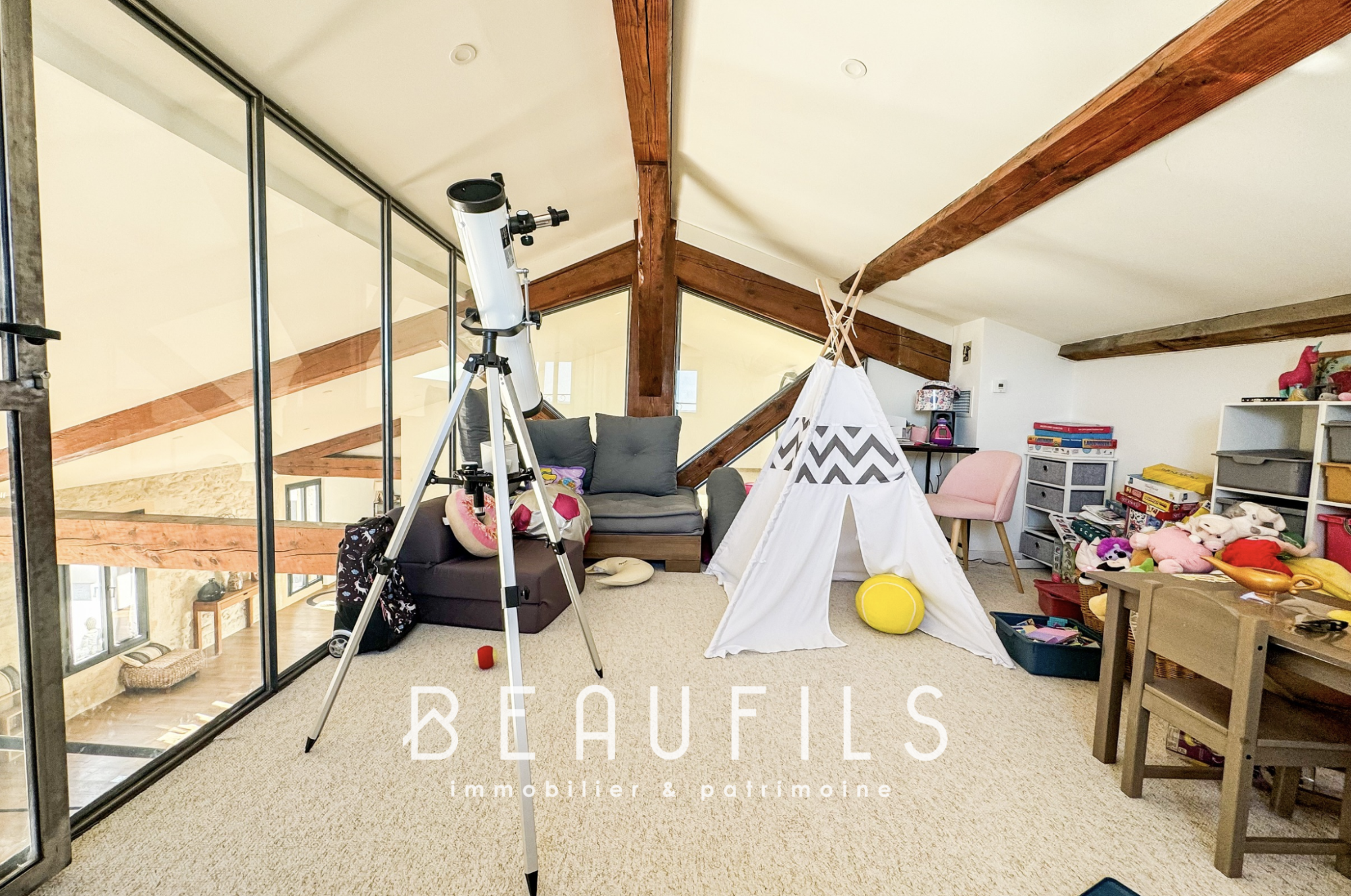 Loft atypique à Mauguio Intérieur d'un loft atypique avec poutres apparentes, télescope et coin jeux pour enfants.