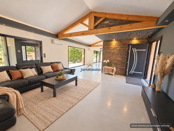 Intérieur d'une propriété moderne avec salon spacieux, canapé noir et décoration en bois.