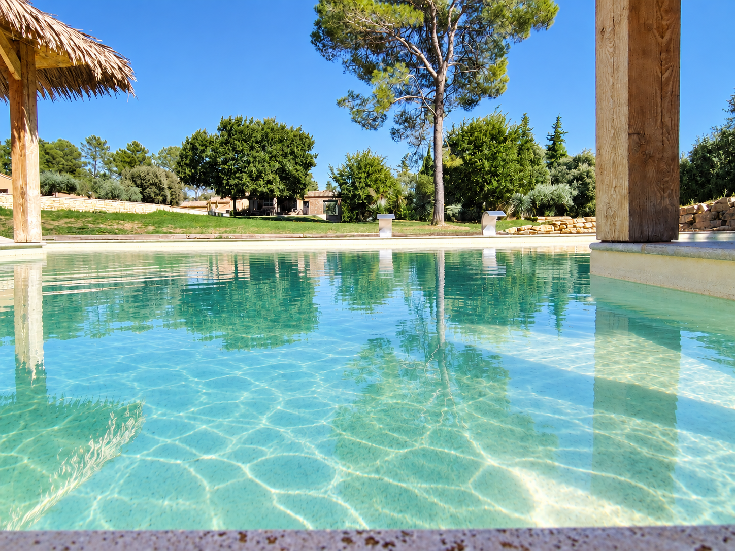 Piscine d’une propriété à Uchaux Vue de la piscine d'une propriété architecturale à Uchaux, avec un parc arboré en arrière-plan.