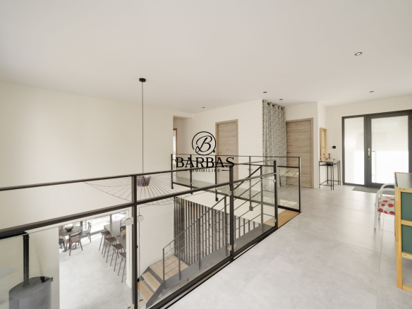 Intérieur d'une maison d'architecte contemporaine avec mezzanine et vue sur un espace de vie.