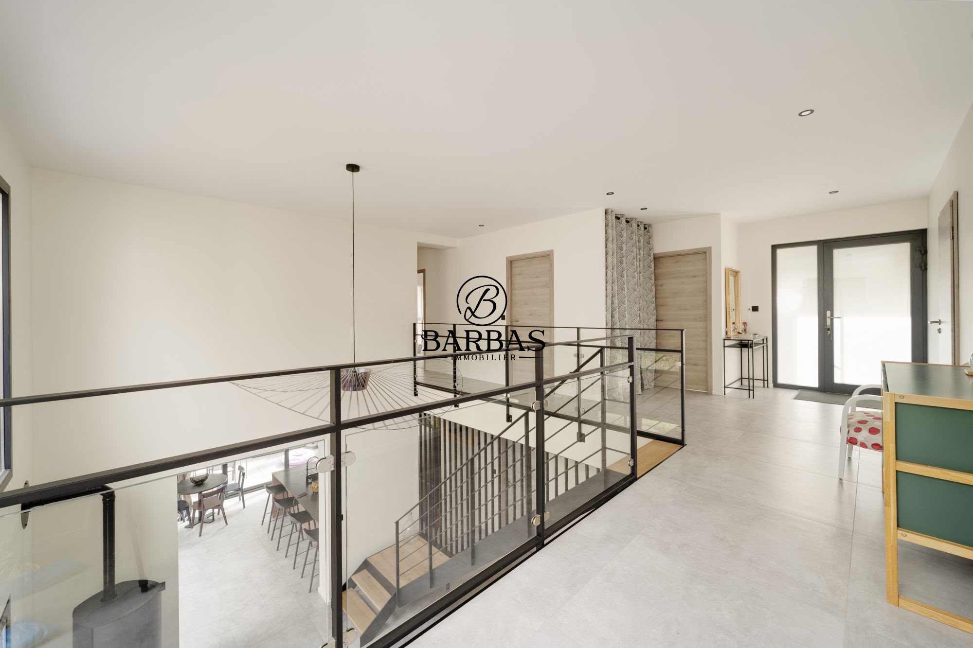 Intérieur d'une maison d'architecte contemporaine avec mezzanine et vue sur un espace de vie.
