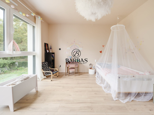 Chambre lumineuse avec lit bébé et décoration douce, fenêtres donnant sur la nature.