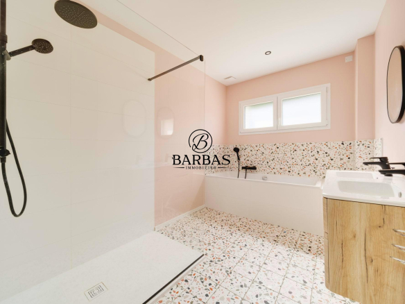 Salle de bains moderne avec douche à l'italienne et baignoire, murs roses et carrelage décoratif.