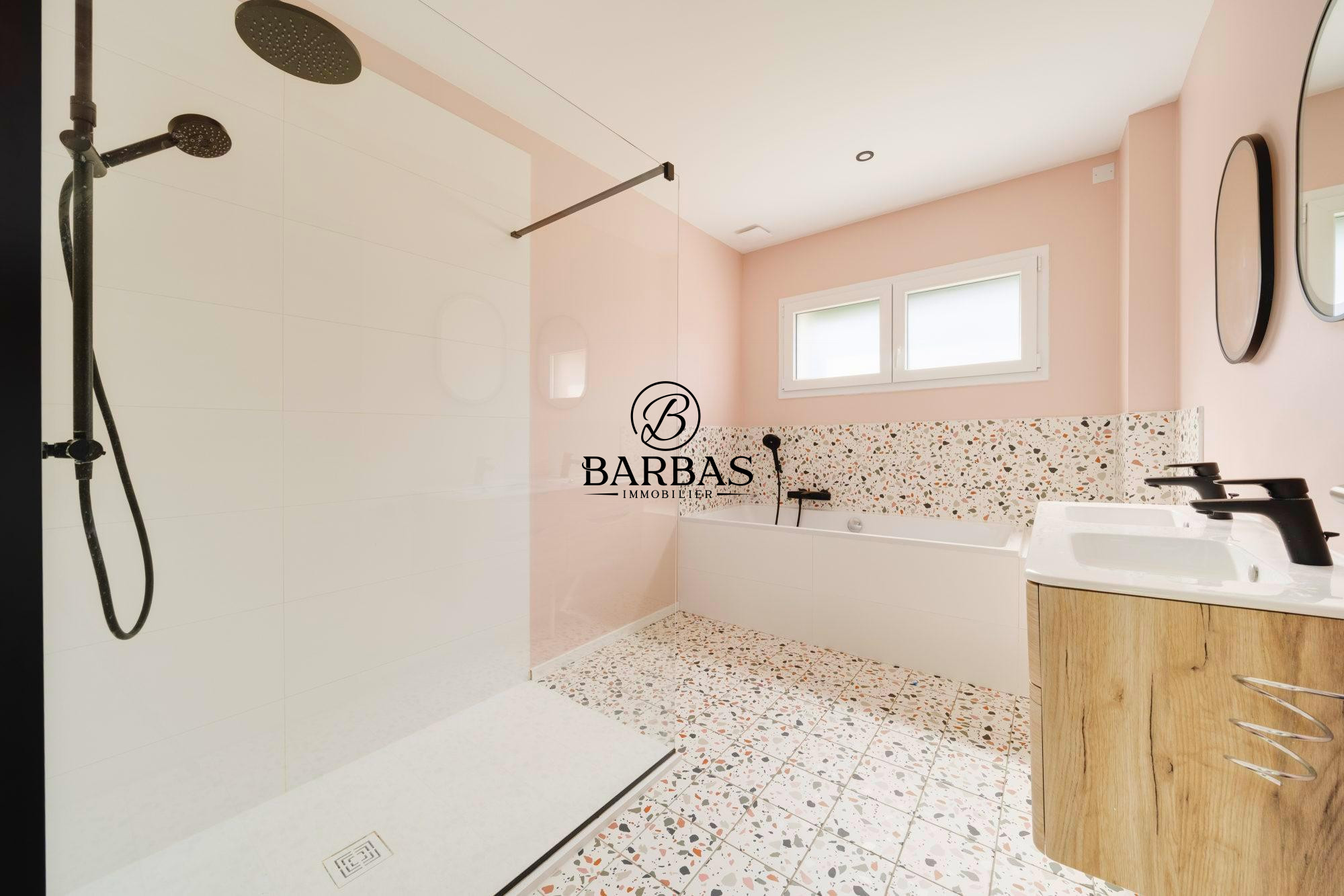 Salle de bains moderne avec douche à l'italienne et baignoire, murs roses et carrelage décoratif.