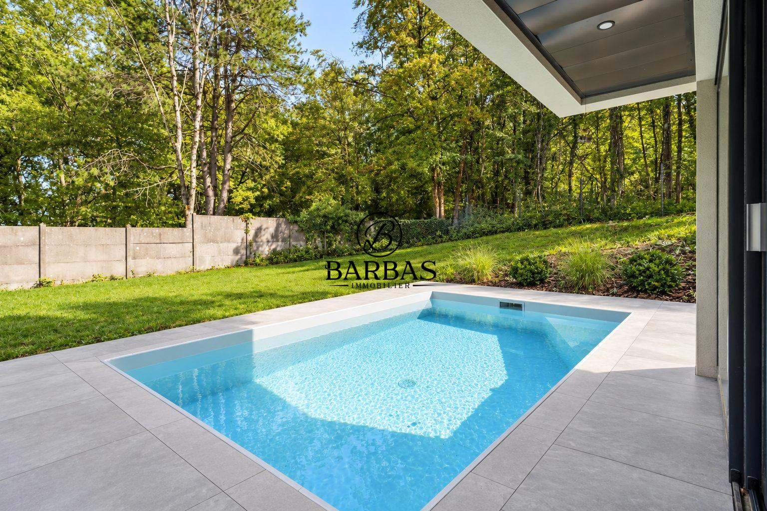 Piscine dans une maison d'architecte contemporaine à Vandoeuvre-lès-Nancy, entourée de verdure.