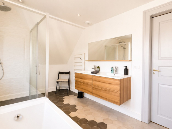 Salle de bains moderne avec douche et baignoire, meuble en bois et miroir, dans une maison rénovée à Munster.