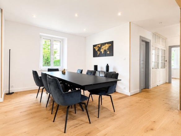 Salle à manger moderne avec table noire et chaises bleues dans une maison rénovée à Munster.
