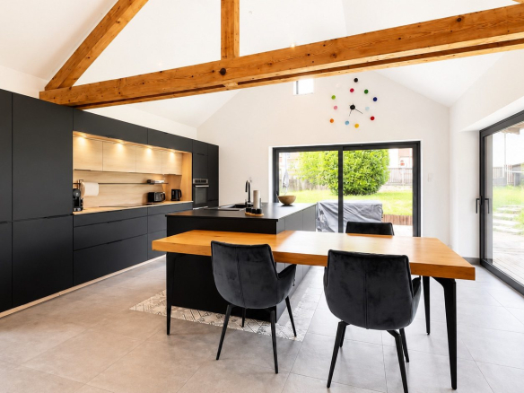 Cuisine moderne avec îlot central et salle à manger, ouverte sur le jardin.