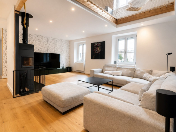 Intérieur d'un salon moderne avec canapé et poêle à bois dans une maison rénovée à Munster.
