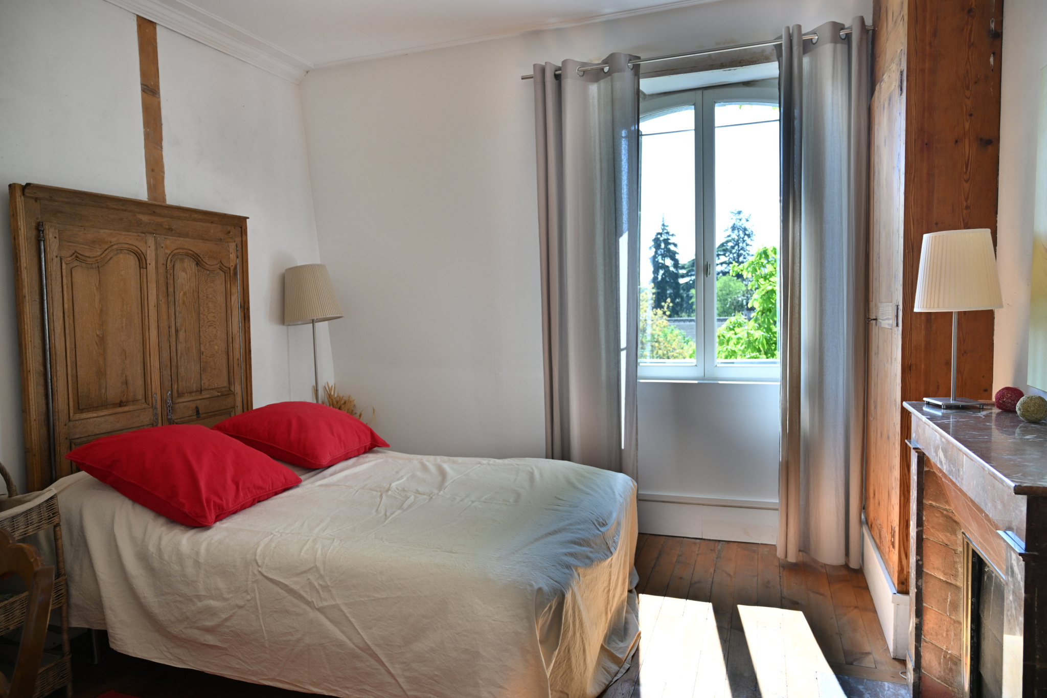Chambre d’une maison de caractère à Étampes Chambre d'une maison de caractère avec lit double et fenêtre offrant une vue sur l'extérieur.