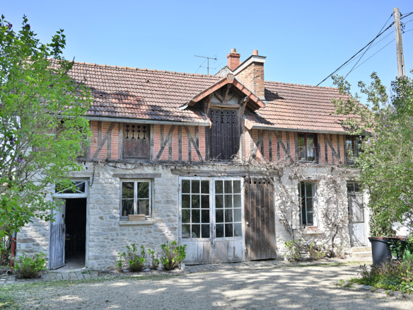 Maison de caractère en pierre avec des éléments en bois, entourée de verdure à Étampes.