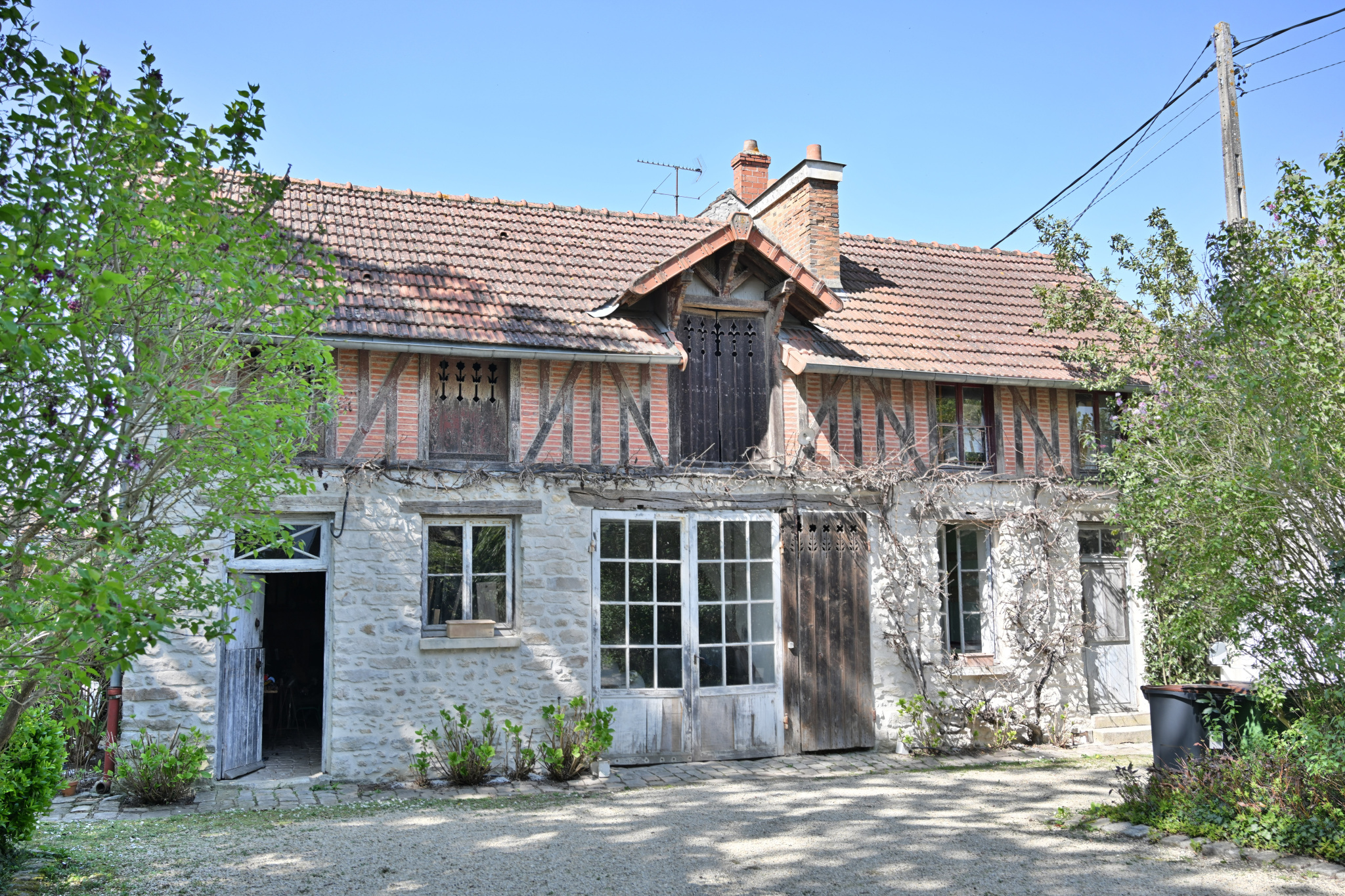 Maison de caractère à Étampes Maison de caractère en pierre avec des éléments en bois, entourée de verdure à Étampes.