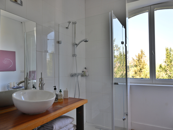 Salle de bain moderne avec douche vitrée et lavabo sur un meuble en bois.