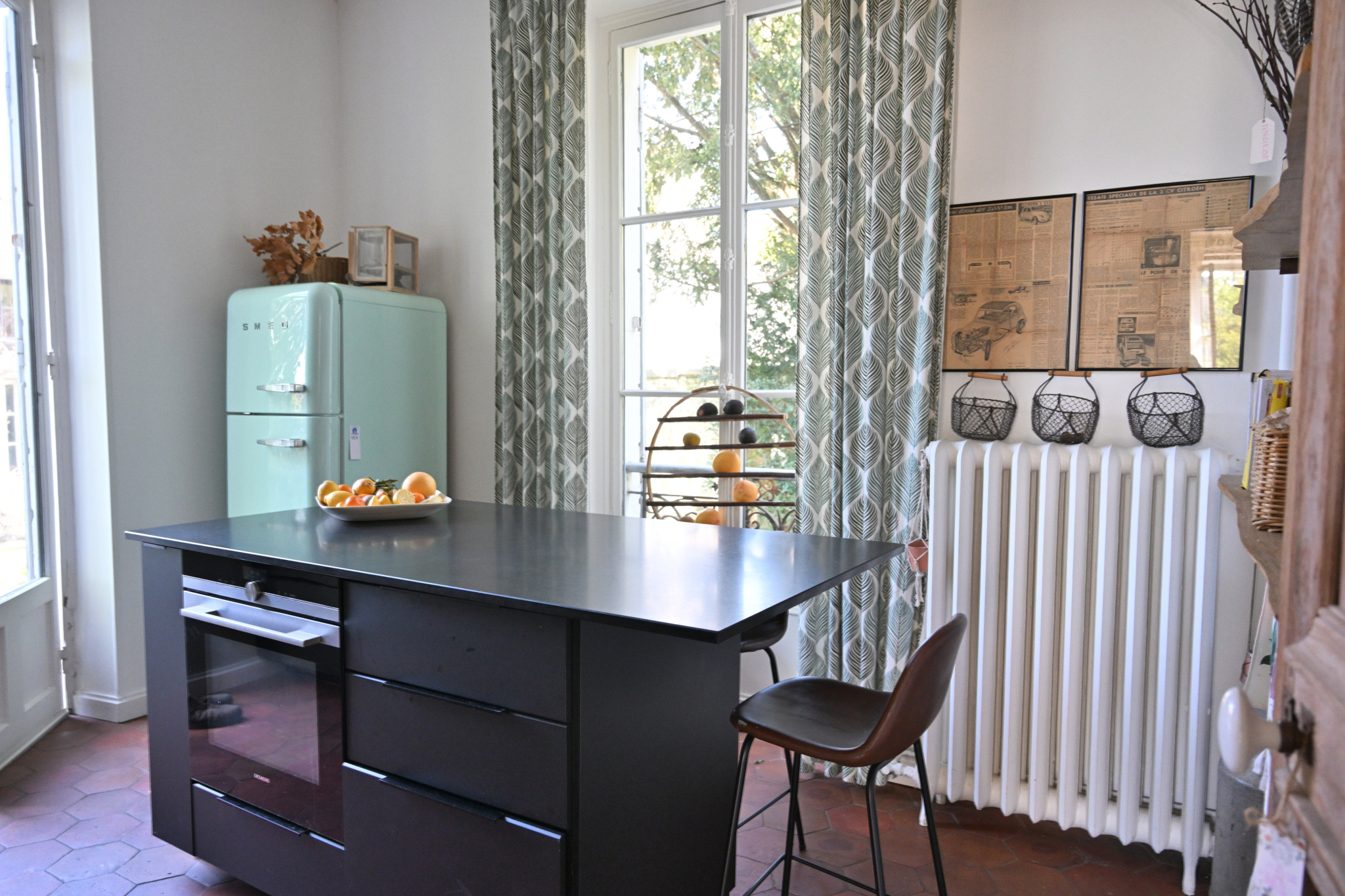 Cuisine d’une maison de caractère à Étampes Cuisine d'une maison de caractère avec un îlot central et un réfrigérateur vintage, fenêtres ouvertes sur l'extérieur.