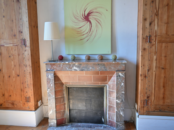 Cheminée en marbre dans une maison de caractère avec murs en bois, décor minimaliste.