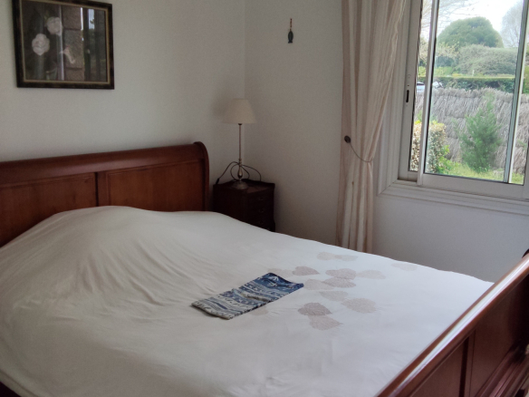 Room with double bed and window overlooking a garden in Carnac.