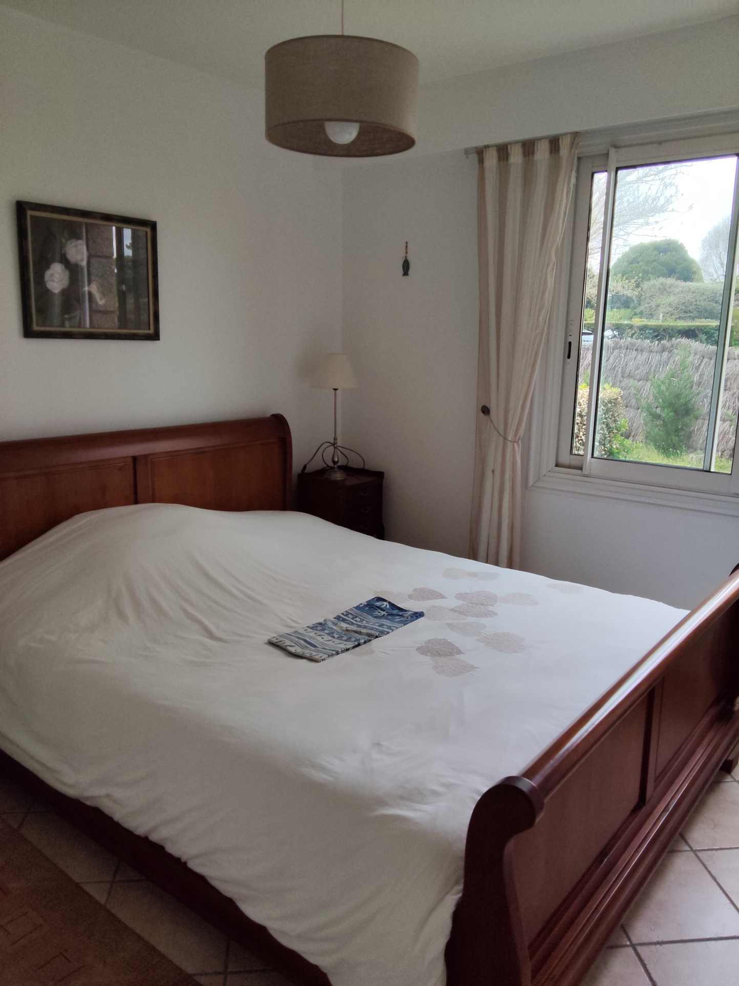 Room with double bed and window overlooking a garden in Carnac.