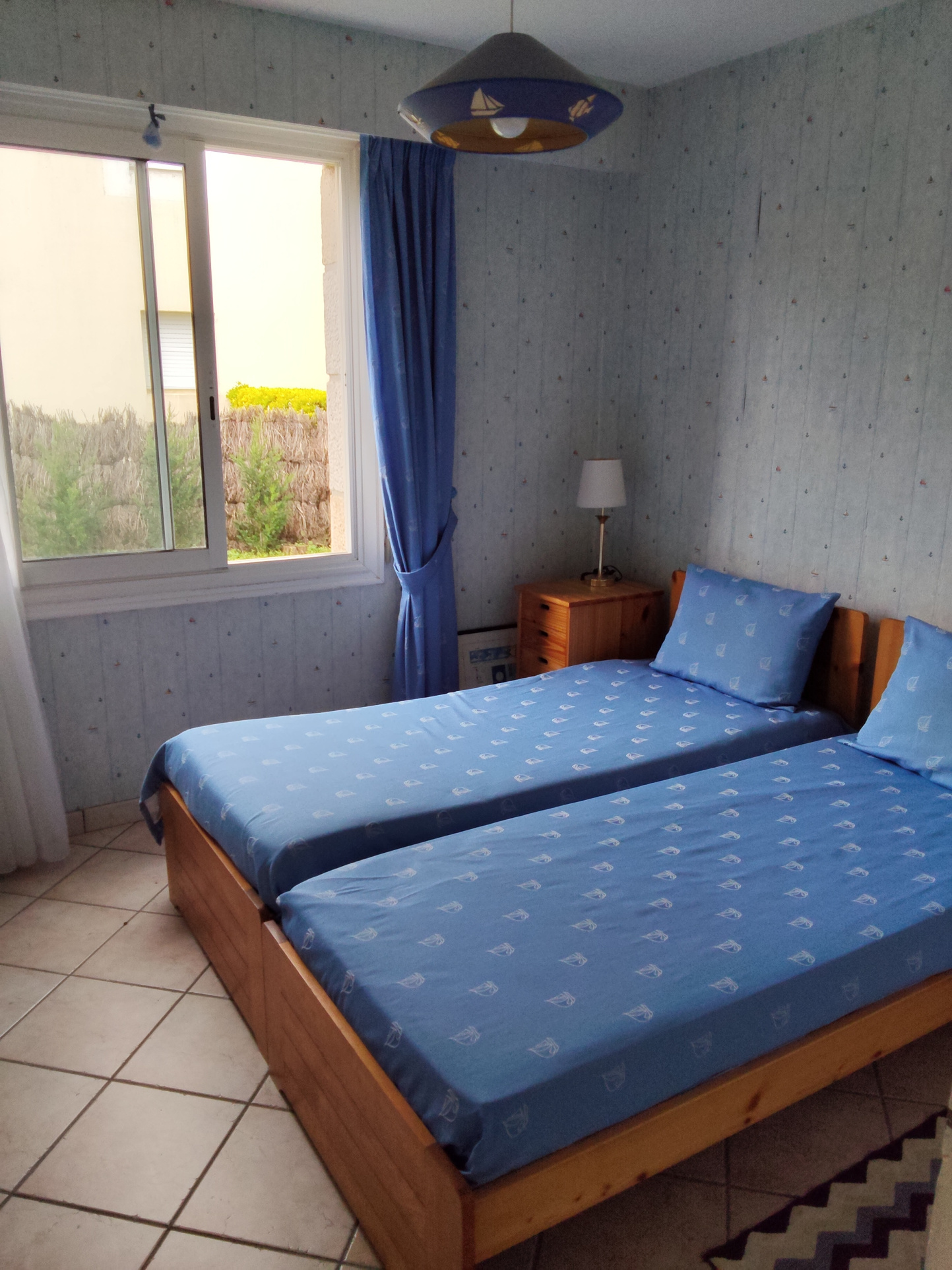 Room with two twin beds and a window overlooking the outside.