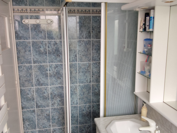 Bathroom with shower and sink, blue tiles, in an apartment in Carnac.