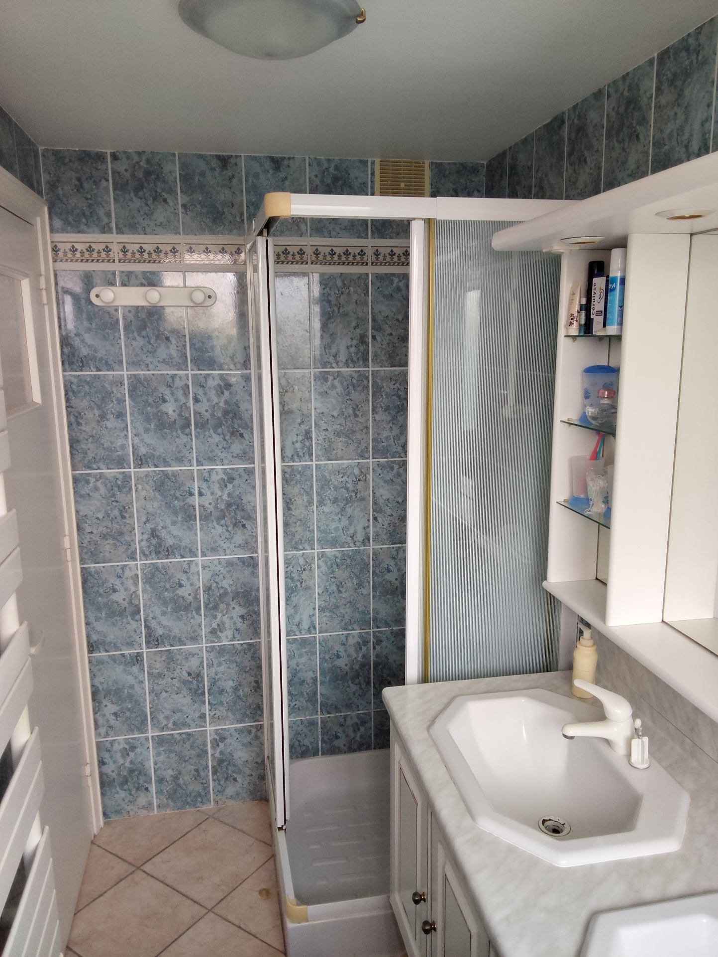 Bathroom with shower and sink, blue tiles, in an apartment in Carnac.