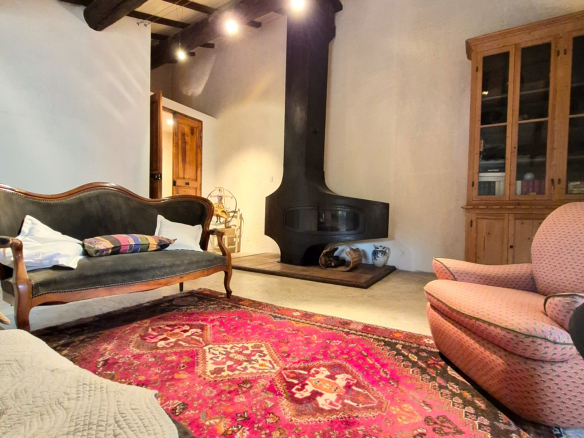 Interior of a farmhouse with fireplace, sofas and colorful rug.